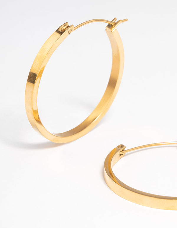 Highlighting waterproof medium flat hoop earrings with gold plated stainless steel construction and hoop closure close up view