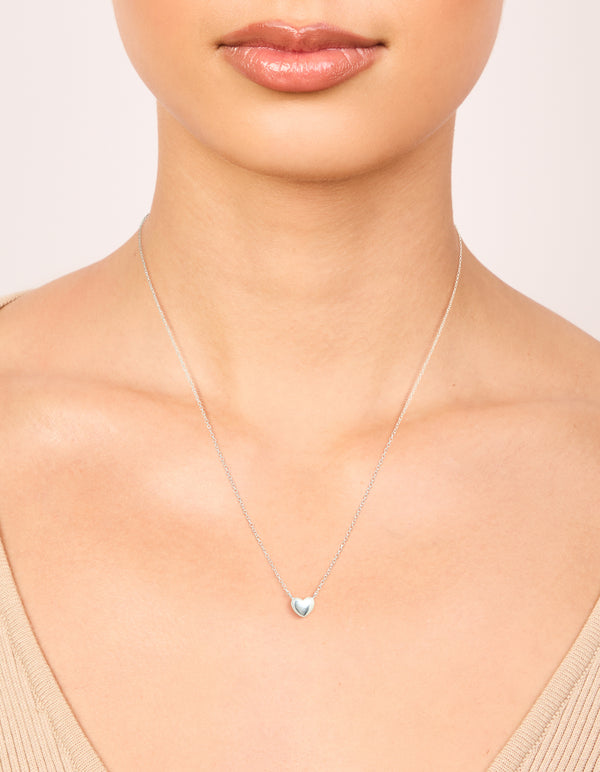 Showcasing a sterling silver mini puffy heart charm pendant necklace with dainty styling on neck view