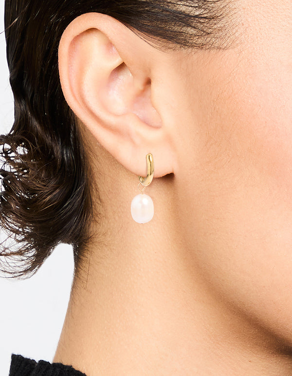 Showcasing waterproof gold plated stainless steel freshwater pearl drop huggie earrings in white on ear view