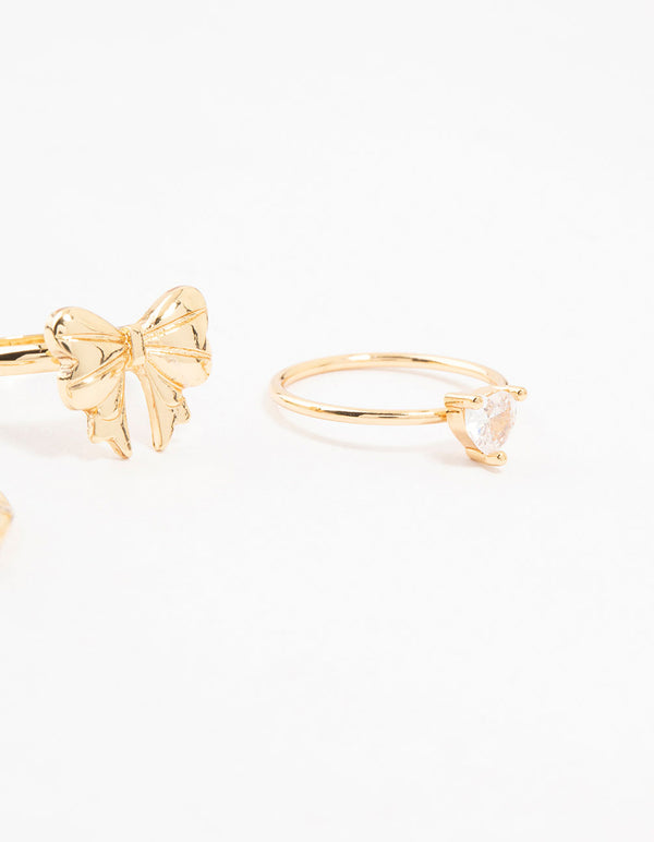 Highlighting gold plated bow and heart stackable rings with cubic zirconia in a 3-pack close up view