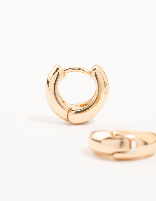 Highlighting gold cubic zirconia oval huggie earrings in a 3-pack with polished finish close up view