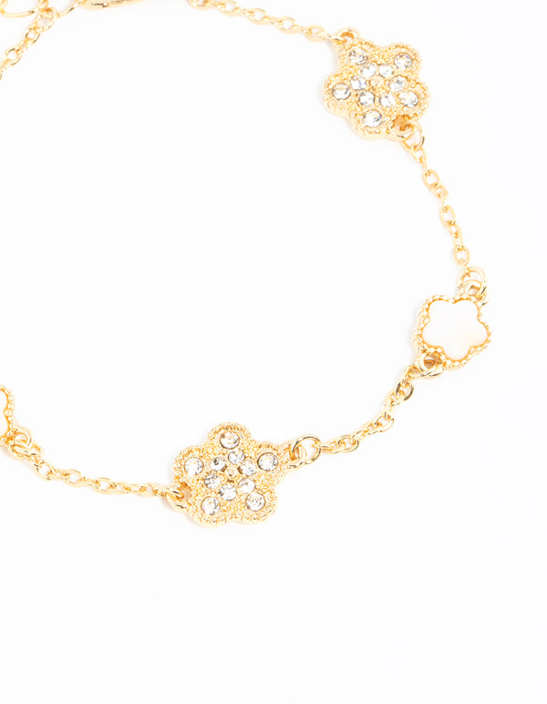 Detailed view of a gold plated alternating small and medium flower bracelet with charm accents in white close up view