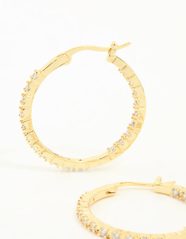 Featuring gold plated statement large skinny hoop earrings with cubic zirconia in close up view