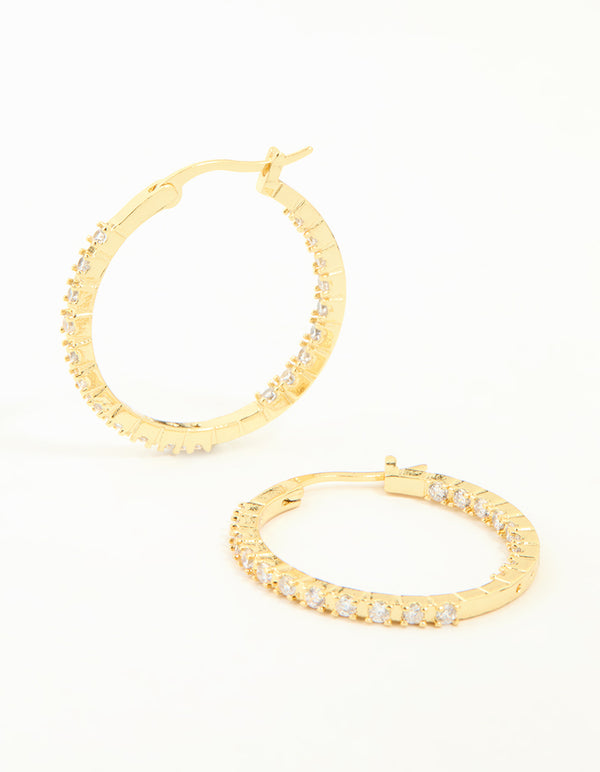 Showcasing statement large skinny hoop earrings in gold plated finish featuring cubic zirconia stones front view