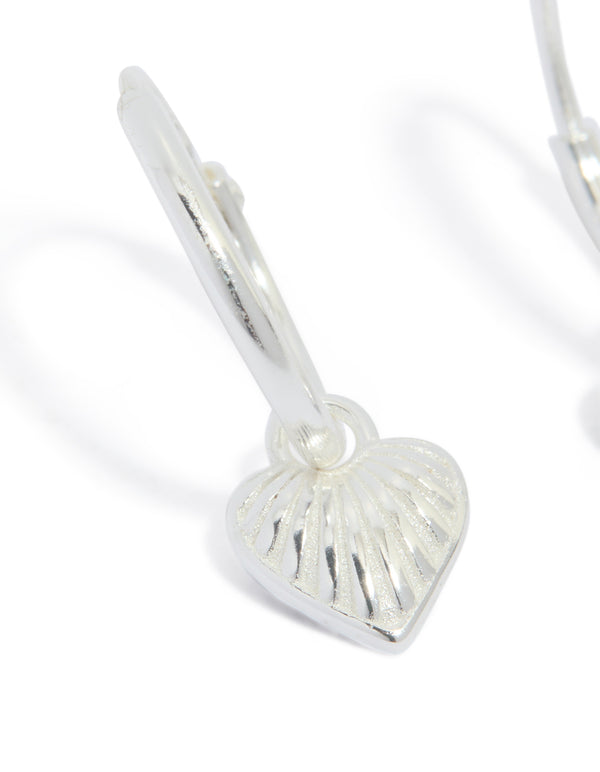 Designed with sterling silver heart huggie earrings in silver close up view