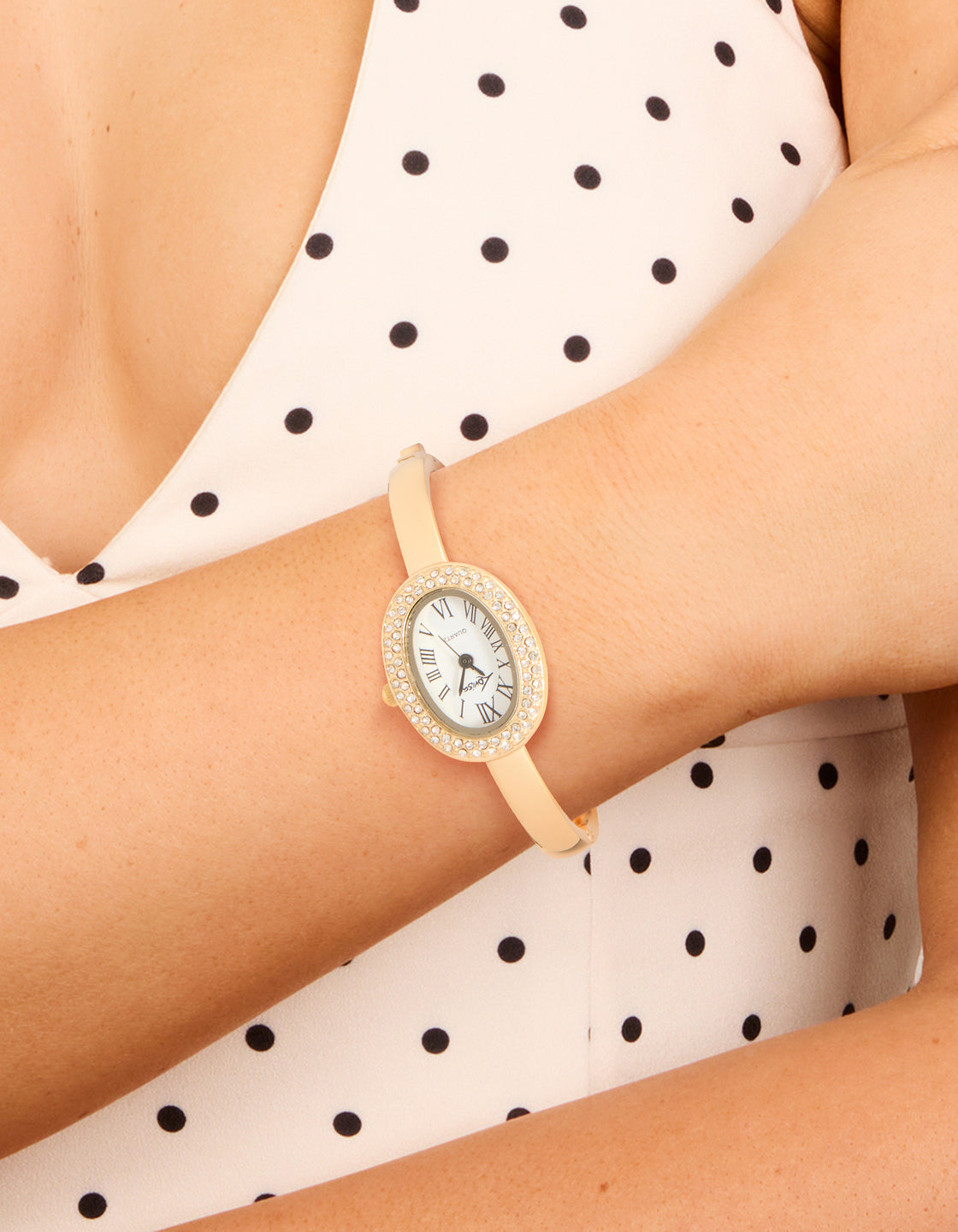Showcasing a gold diamante oval bangle watch featuring white dial with roman numerals, statement style for women, designed for casual occasions with analog display on wrist view