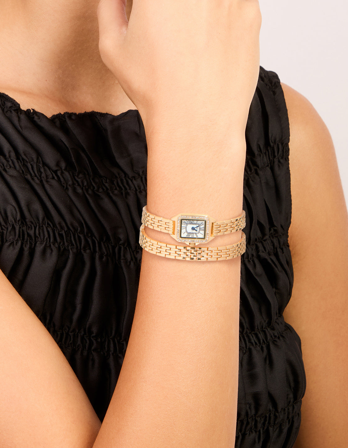 Showcasing this gold diamante mini double strap watch with blue dial featuring roman numerals, rectangle shape, women's formal analog timepiece with link band on wrist view