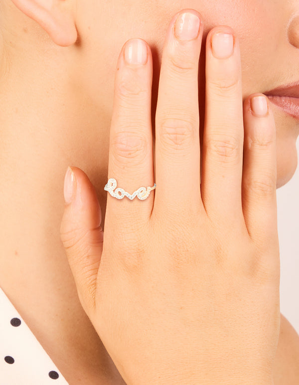 Showcasing a sterling silver cubic zirconia love ring with script detailing and statement style in clear stone on finger view