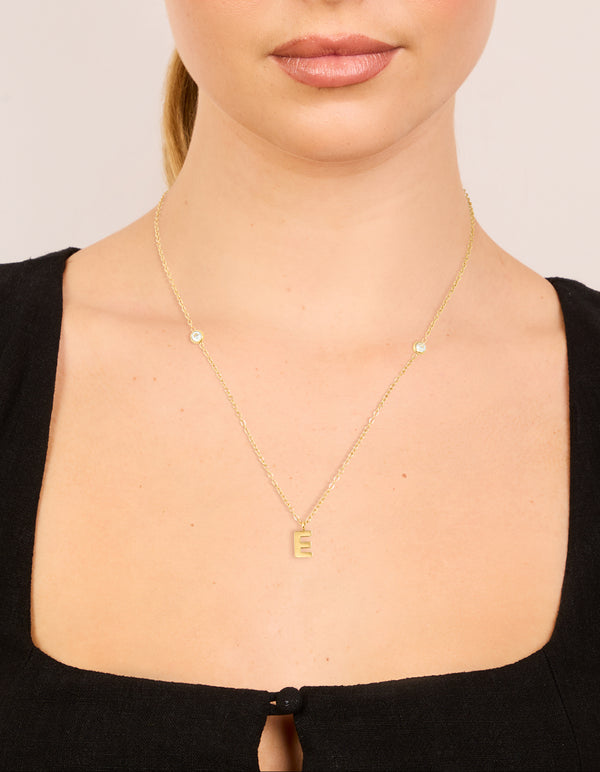 Showcasing a waterproof pendant necklace with letter E initial in gold plated stainless steel featuring dainty design on neck view