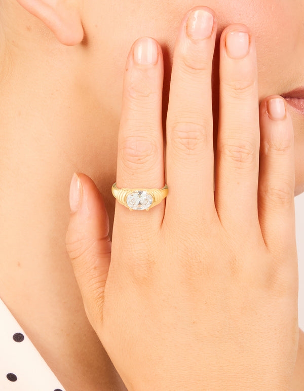 Showcasing a waterproof ring crafted from stainless steel with oval cubic zirconia in gold plated ribbed design on finger view