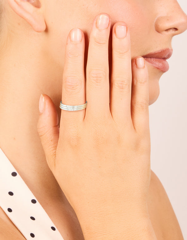 Featuring waterproof stainless steel with cubic zirconia accents, this thin trio rings 3-pack in silver and clear stone on finger view