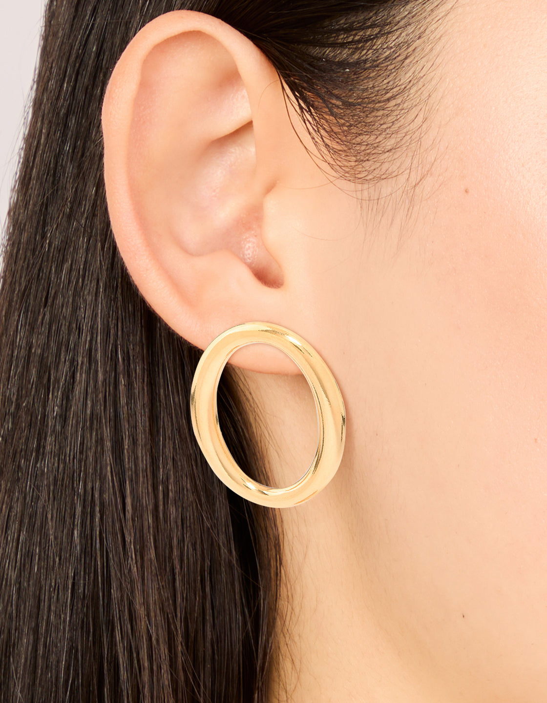 Crafted from waterproof stainless steel oval open doughnut stud earrings with gold plated finish on ear view