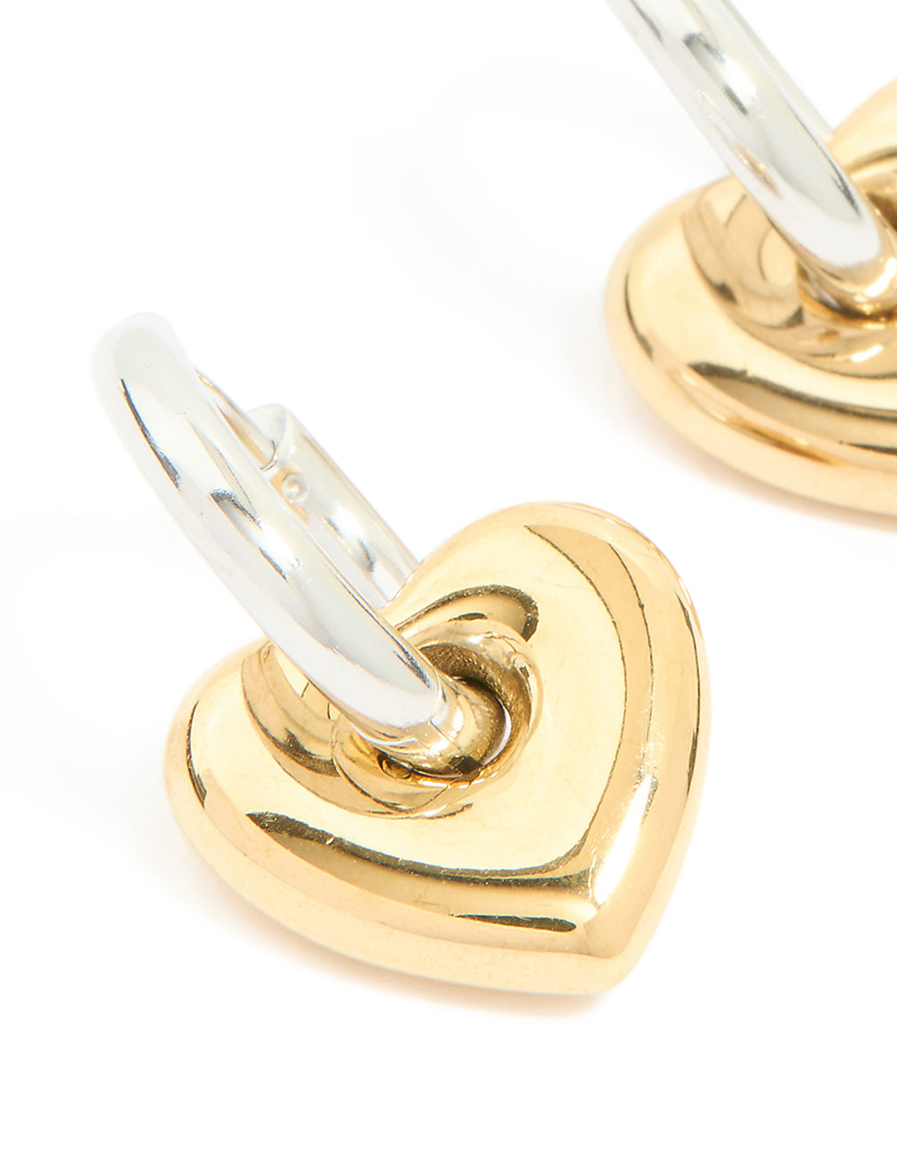 Highlighting waterproof mixed metal plated small heart huggie earrings in stainless steel with gold and silver tones close up view