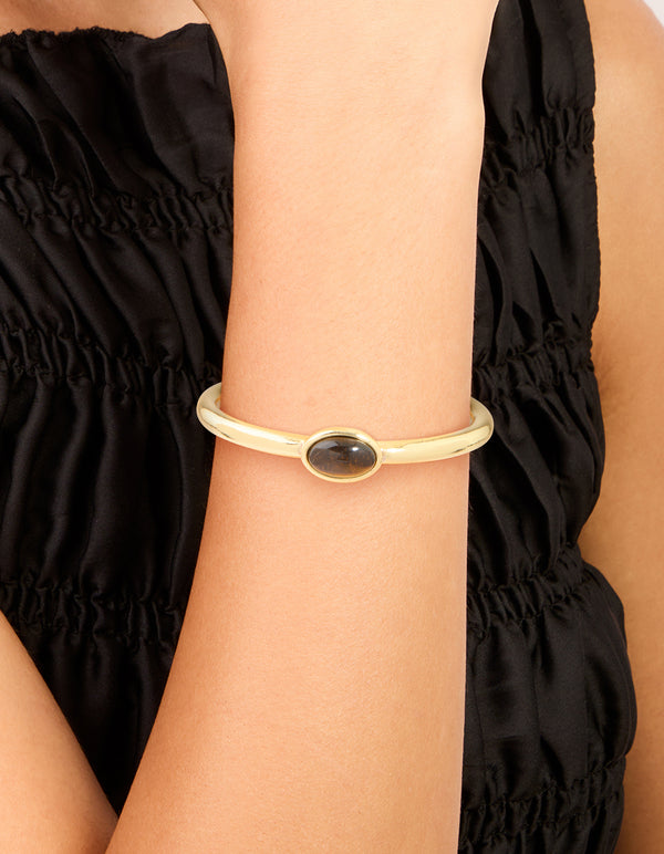 Showcasing a waterproof gold plated stainless steel open wrist cuff with tigers eye semi precious stone on wrist view