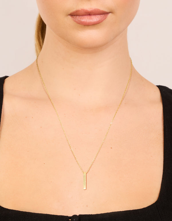 Showcasing a waterproof bar pendant necklace crafted from stainless steel pillar with engravable features in gold plated finish on neck view