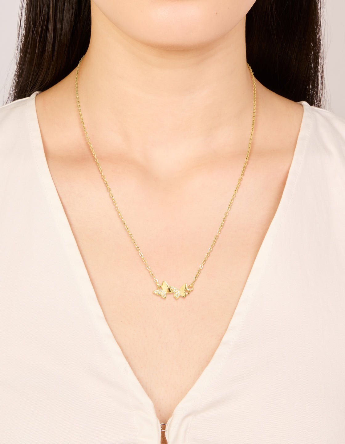 Showcasing a waterproof butterfly pendant necklace crafted from stainless steel in gold plated finish with cubic zirconia and dainty styling on neck view