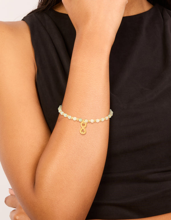 Showcasing a waterproof gold plated stainless steel semi precious infinity stretch bracelet with beads on wrist view