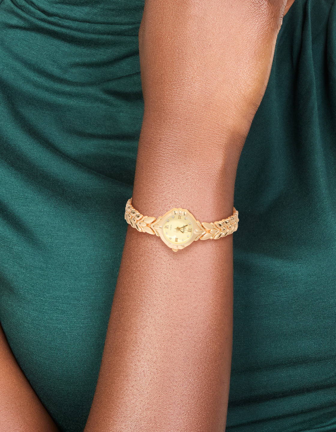 Showcasing a vintage watch with leaf detailing, gold dial featuring Roman numerals in a round shape, designed for women's casual occasions with a link-band strap in gold and analog type on wrist view