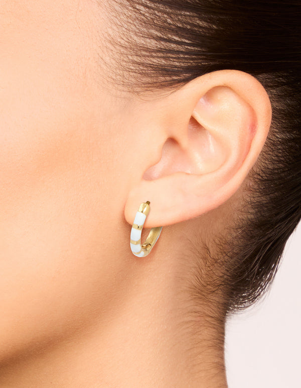 Showcasing waterproof gold plated stainless steel white enamel bamboo huggie earrings on ear view