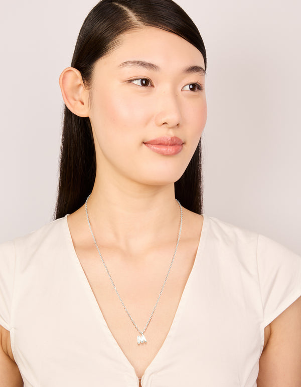 Featuring a waterproof stainless steel mini bubble letter M necklace with initial pendant in silver plated on model view