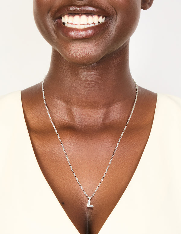 Featuring a waterproof mini bubble letter L necklace with initial pendant in stainless steel silver and dainty design on neck view
