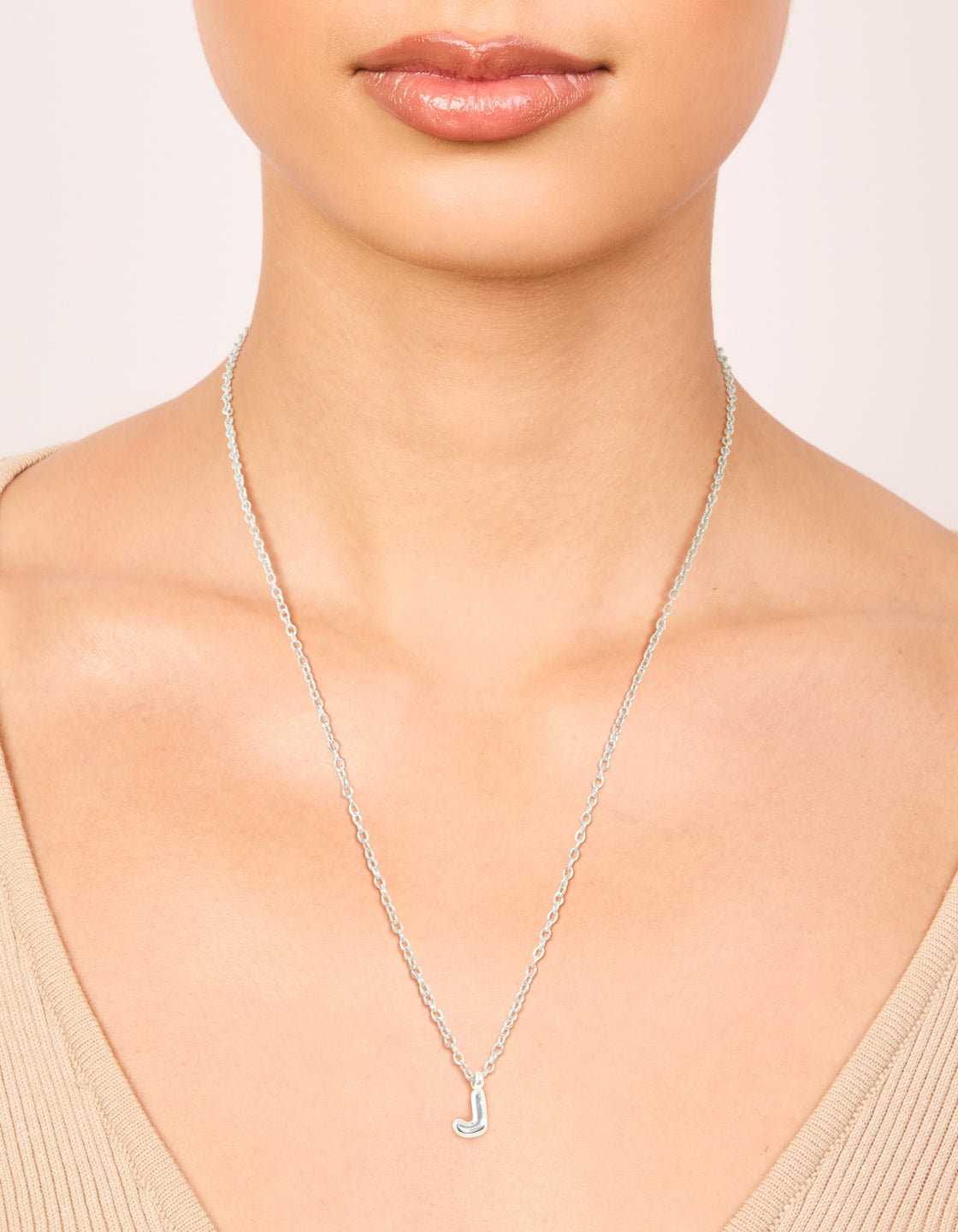 Styled waterproof stainless steel mini bubble letter J necklace with featuring initial pendant in silver on neck view