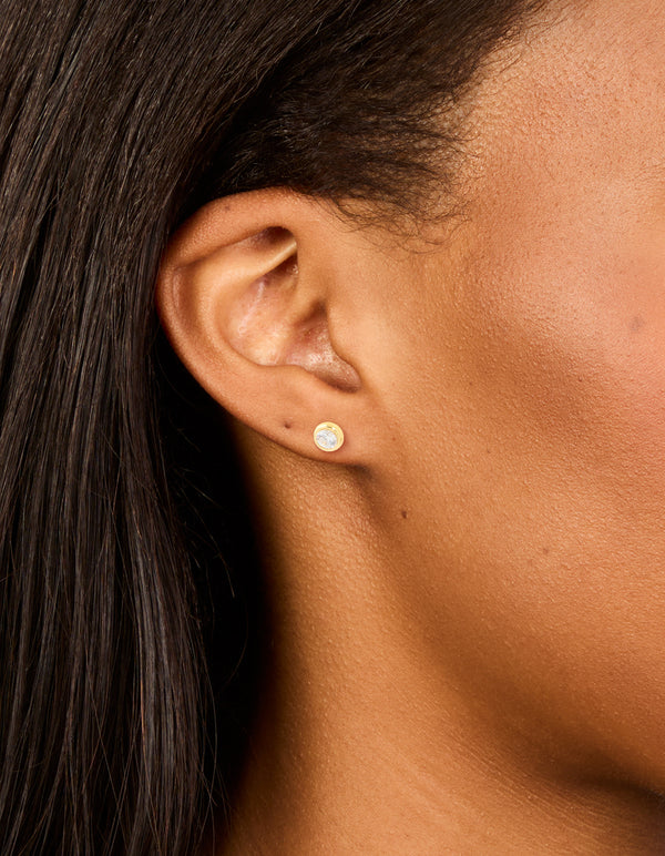 Beautifully crafted waterproof gold plated stainless steel bezel set stud earrings featuring round cut cubic zirconia on ear view