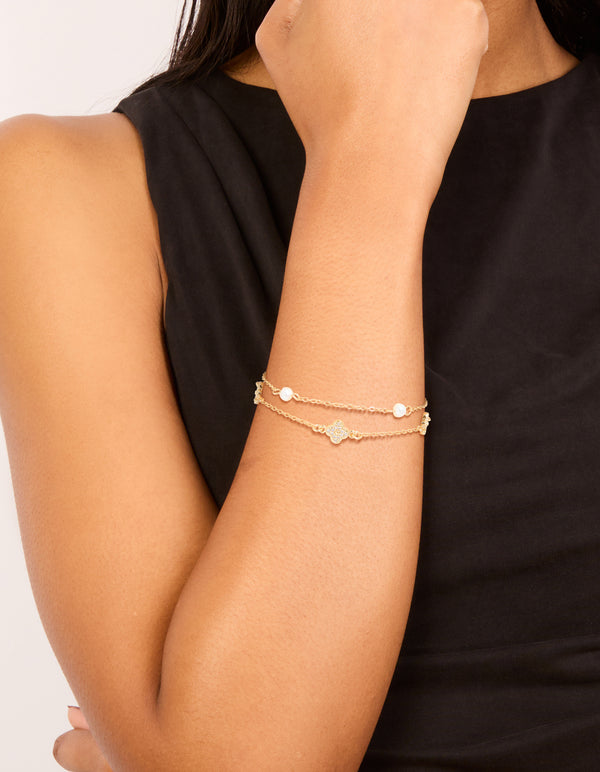Featuring a dainty gold plated bracelet with cubic zirconia flower and freshwater pearls in a layered design on wrist view