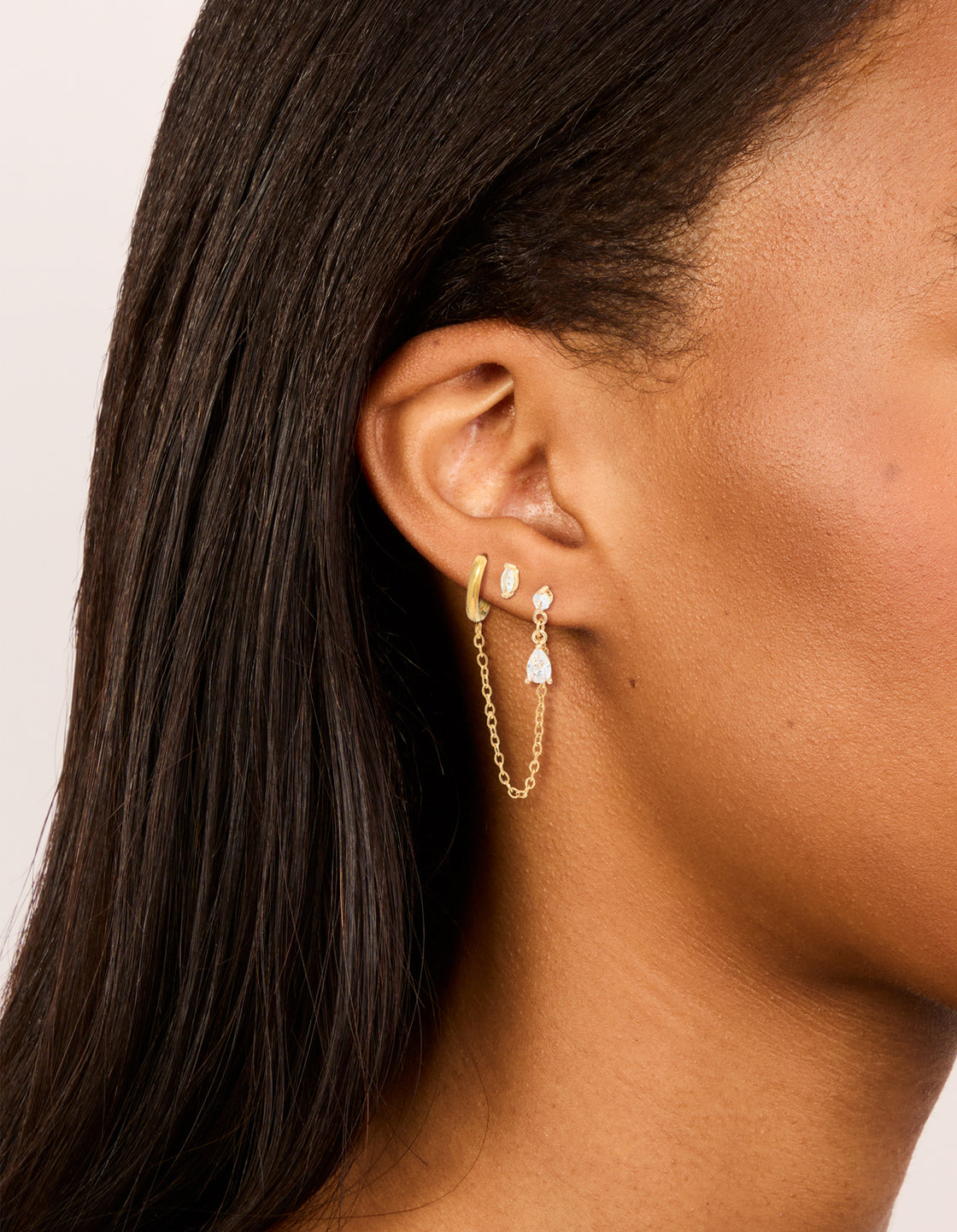 Showcasing waterproof gold plated stainless steel mixed cubic zirconia stud earrings 2-pack with marquise stone cut and huggie closure in gold on ear view