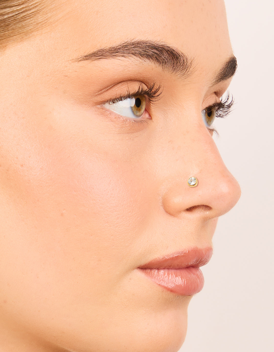 Showcasing gold plated titanium bezel threadless flat back nose studs with bar detail, balls accent, diamond embellishment, and hoop closure nose view
