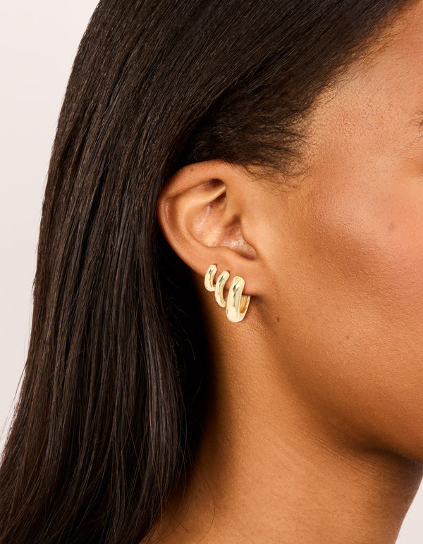 Showcasing gold plated thick hoop earrings in a 3-pack on ear view