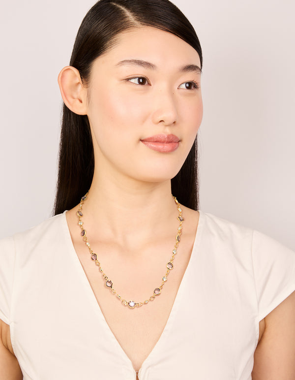 Highlighting a gold plated station necklace with pink and clear cubic zirconia stones in round cut on model view