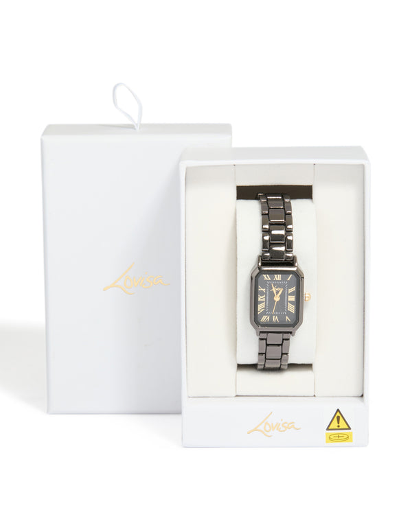 Presenting a black coated metal rectangle roman numeral watch with gold numerals, analog display, link band, and formal styling case detail view