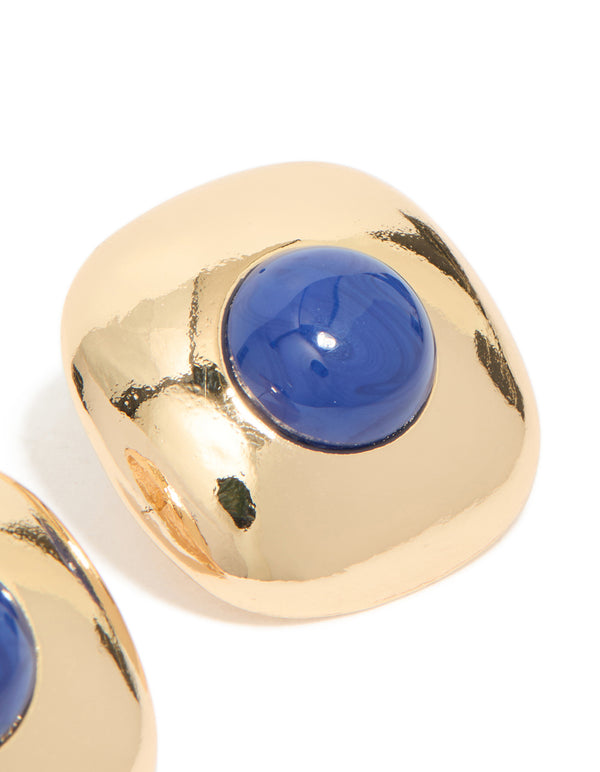 Designed with gold and dark blue acrylic medallion these statement stud earrings featuring royal accents in a post detail view