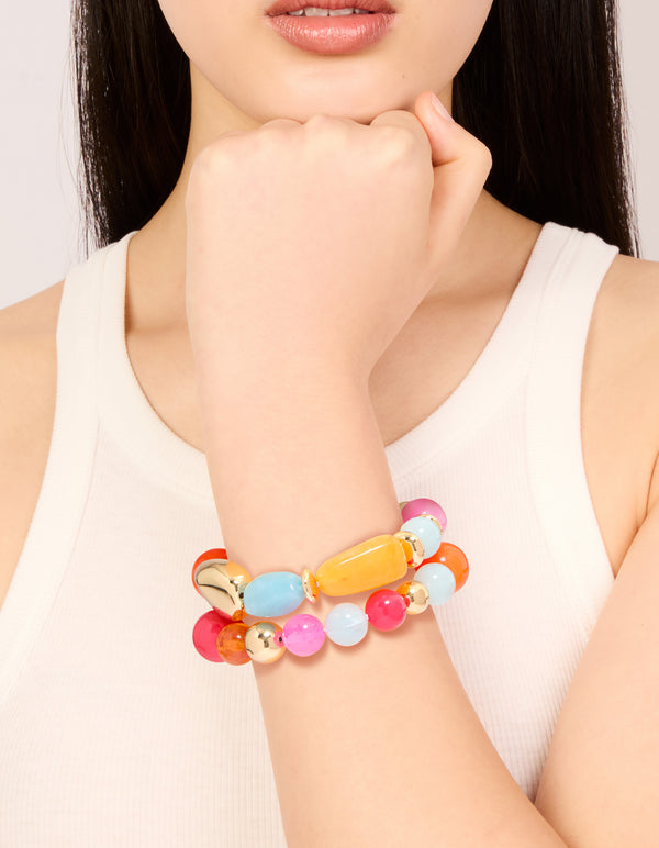 Showcasing acrylic beaded stretch bracelets in orange, pink, light blue, and gold in a 2-pack on wrist view