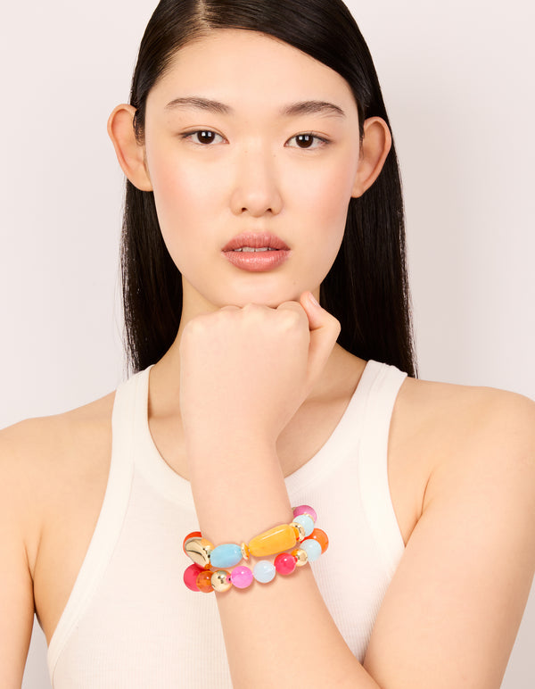 Elegant acrylic beaded stretch bracelets in orange, pink, light blue, and gold in a 2-pack on model view