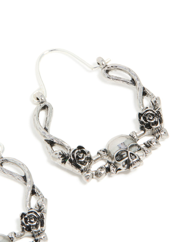 Highlighting statement hoop earrings with skull featuring floral pattern in silver post detail view