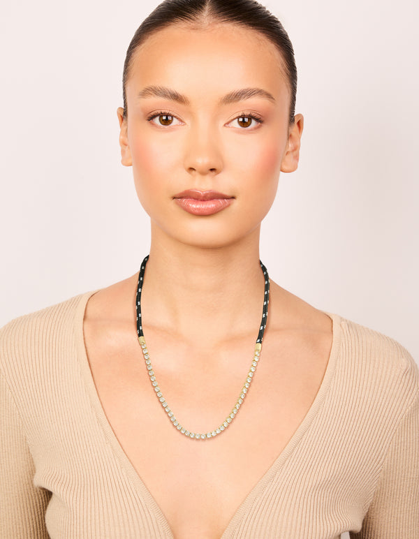 Worn waterproof tennis necklace made from gold plated stainless steel with black cord in statement style on model view