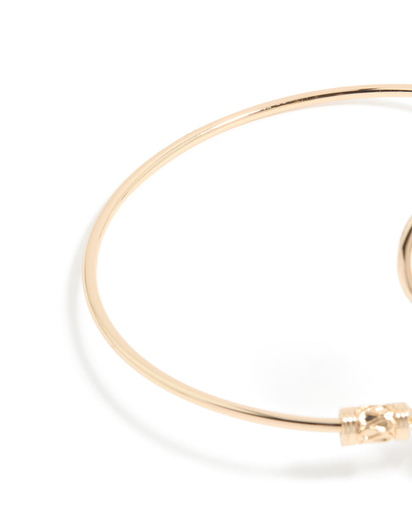 Designed with celestial sun detailing and a swirl design, this gold statement cuff is shown in closure detail view