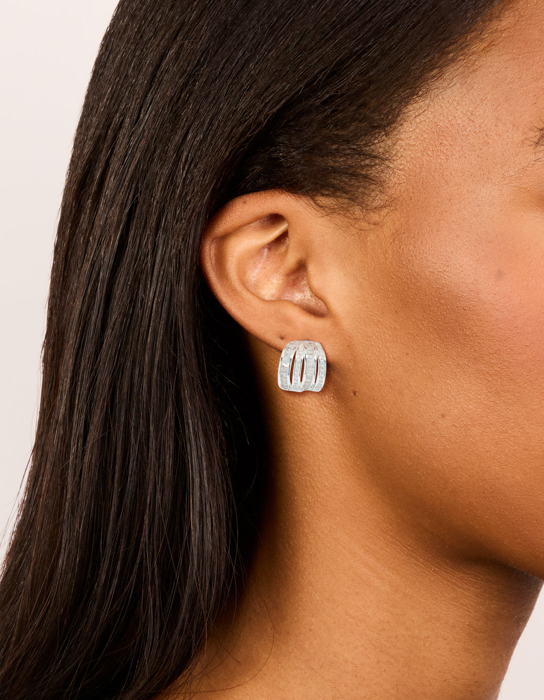 Featuring silver plated cubic zirconia 4 layered huggie earrings on ear view