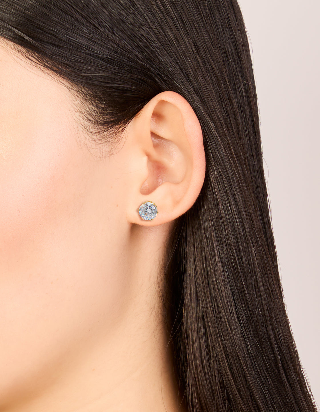 Showcasing statement stud earrings with round cut cubic zirconia in waterproof gold plated stainless steel on ear view