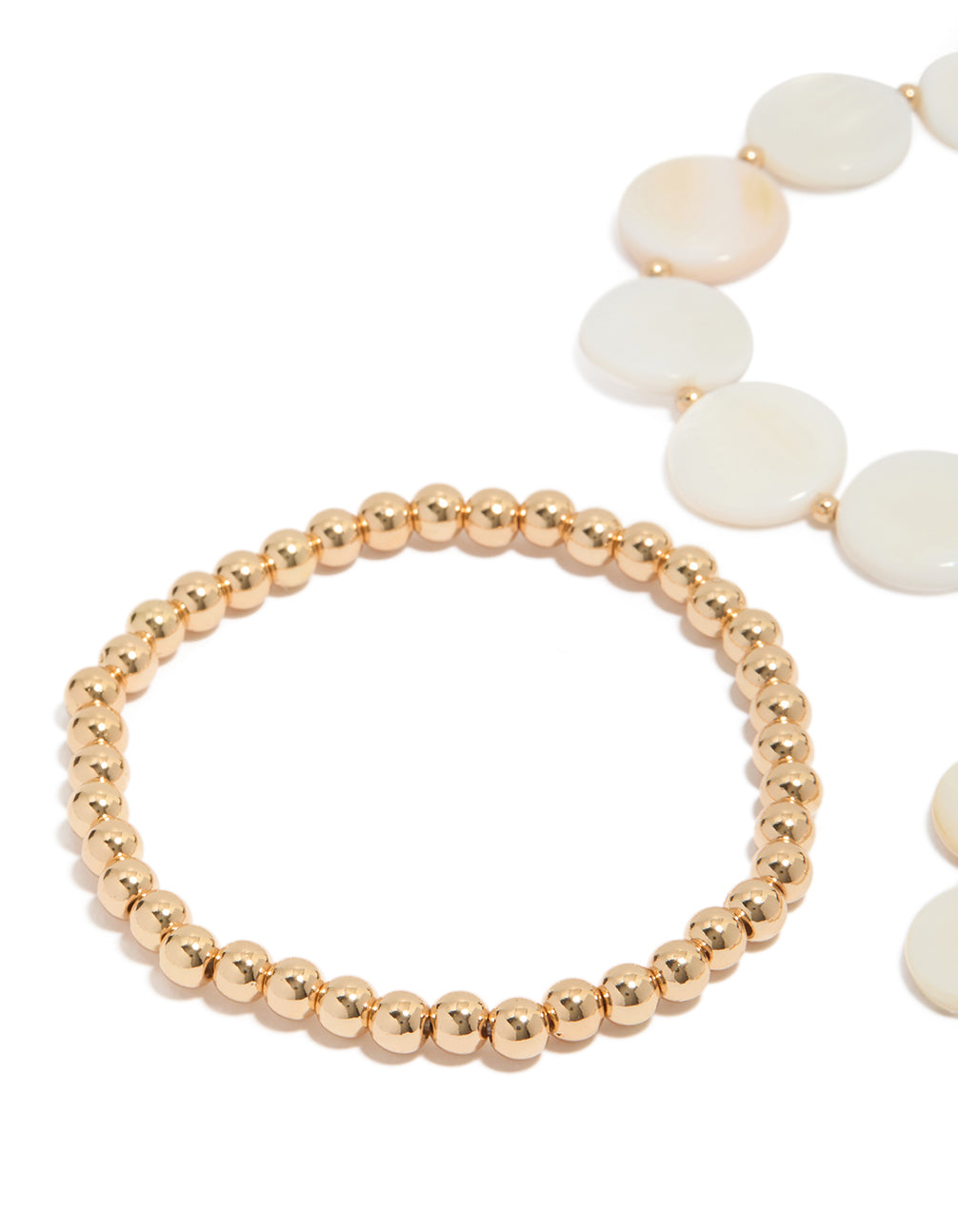 Showcasing gold beaded and genuine shell discs bracelets 4-pack with ocean-inspired design in ivory and beige close up view