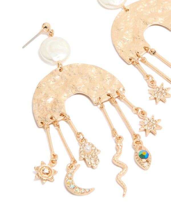 Featuring brushed gold rainbow and celestial drop earrings with statement style featuring pearl, evil-eye, hamsa hand, snake, moon, sun, star charms with pearl close up view