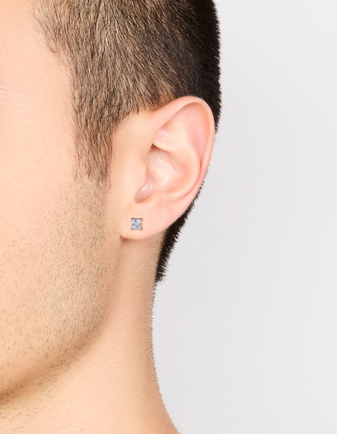 Presenting mens waterproof mini square clear cubic zirconia stud earrings in stainless steel with silver on ear view