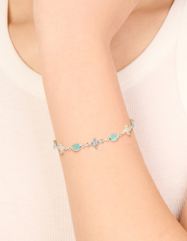 Showcasing a silver plated cubic zirconia clover and blue oval bracelet turquoise accents and clear stones on wrist view
