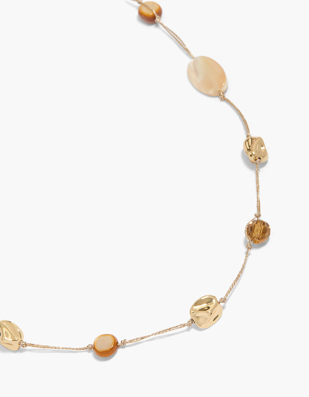 Showcasing a gold plated brown and cream stone cord necklace featuring beads in a statement style close up view
