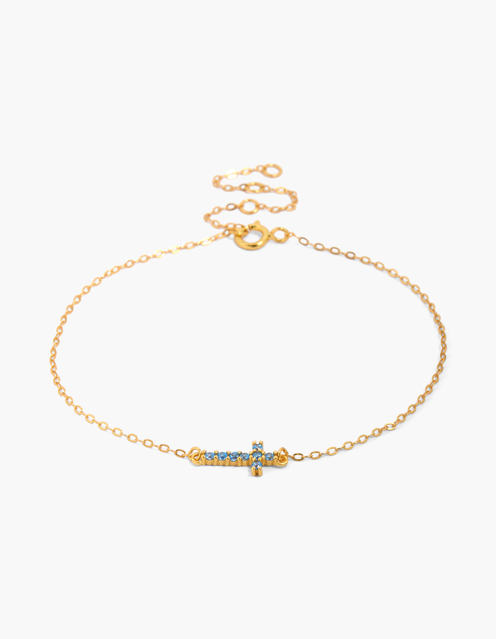 Showcasing a gold plated sterling silver bracelet featuring a cross with light blue cubic zirconia in a dainty style front view