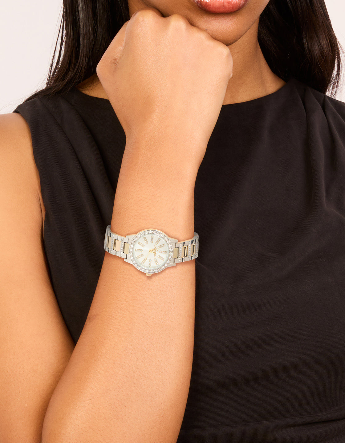 Showcasing women's watch with clear stone dial, round shape, formal styling, multi-color link band strap, and gold analog accessory on wrist view