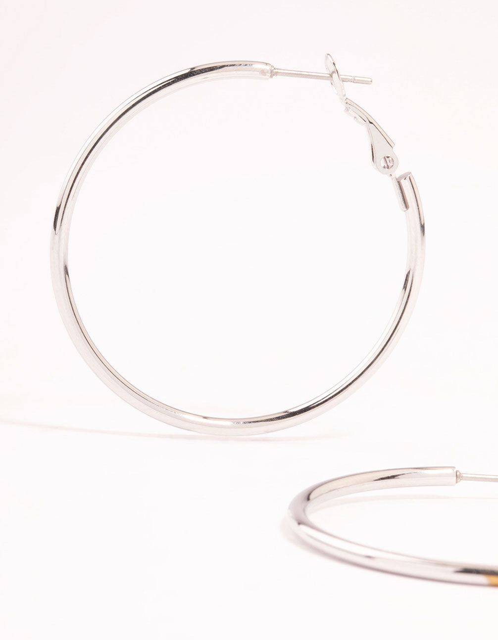 Featuring surgical steel thin hoop earrings in silver with hoop closure close up view