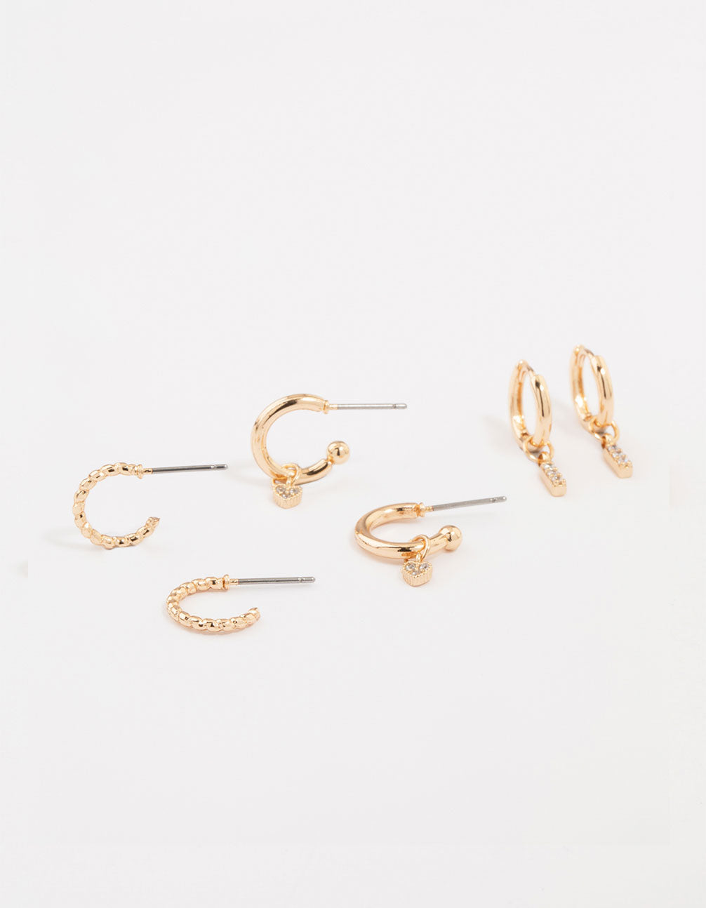 Showcasing gold cubic zirconia heart and twisted huggie earrings in a 3-pack with bar and charm details front view